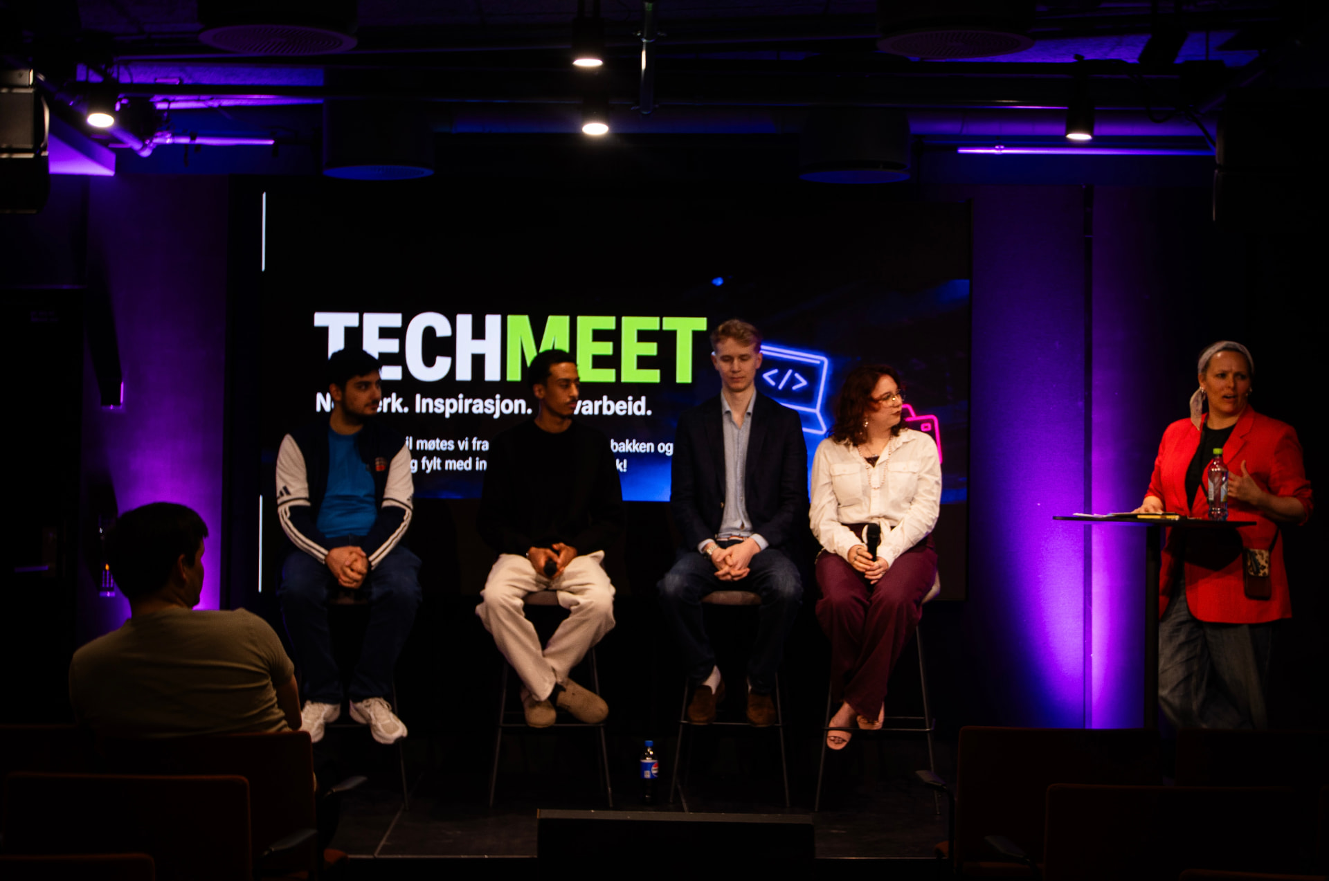 Paneldiskusjon på TechMeet-scenen i Oslo, med TECHMEET-logoen på skjermen i bakgrunnen