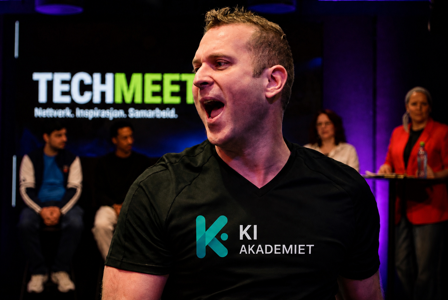 Robin Laumb fra KI Akademiet holder foredrag på TechMeet-scenen i Oslo, med TECHMEET-logoen på skjermen i bakgrunnen